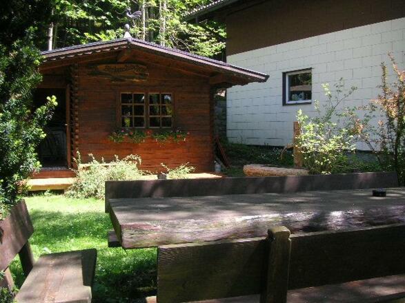 Holzhütte und -sitzgruppe im Garten