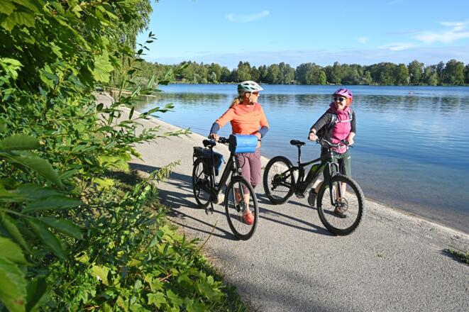 Radler schieben ihre Räder am Olchinger See