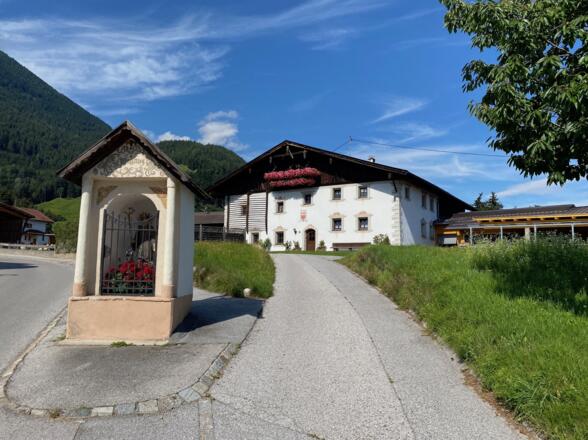 An diesem alten Erbhof mit Bildstöckl führt die Fahrt linkerhand hinauf bis zum Waldrand oberhalb von Ranggen.
