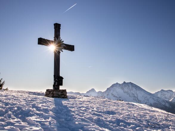 Sonnenstern am Kreuz und der Watzmann am Horizont.