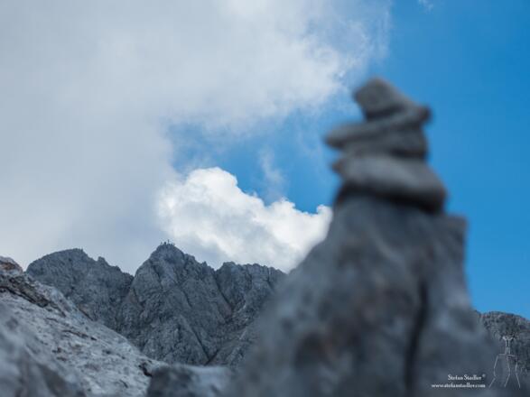 Steinmann auf der Blaueisspitze mit Hochkalter im Hintergrund.