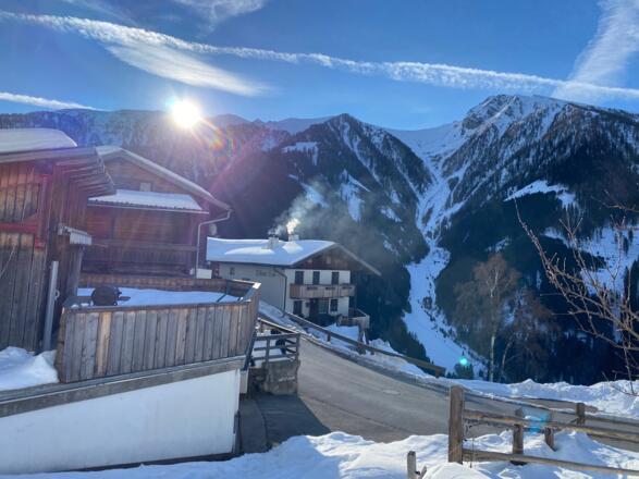 Bei einem Bauernhof am Oberweg quert man die Straße und steigt zu einem Feld empor.