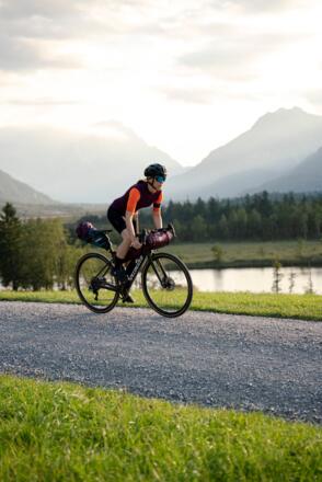 Eine Gravelbikerin fährt auf einem Feldweg entlang des Geroldsees in der Zugspitz Region.
