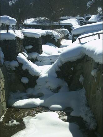 zugefrorener gebirgsbach am Hotel