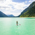 Fjordartiger Sylvensteinsee mit SUP-Paddler