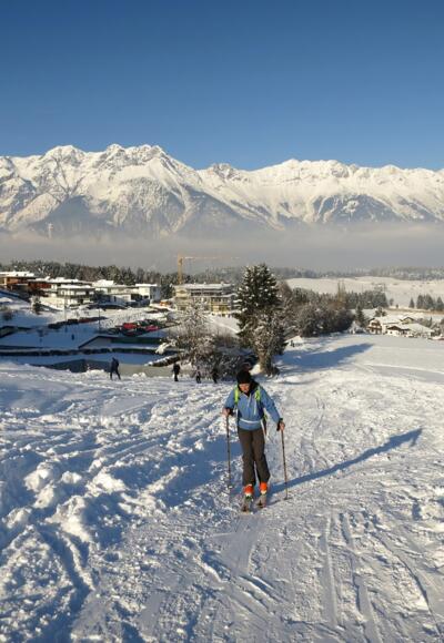 Start vom Parkplatz in Richtung Gasthaus Lärchenwald. Hinten die Nordkette (Karwendel).