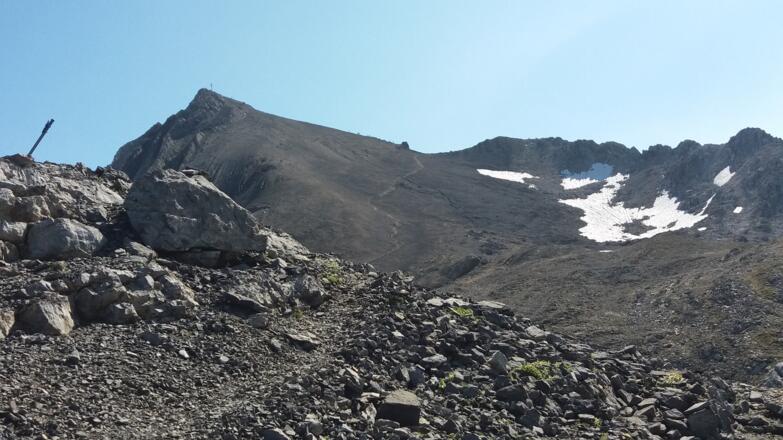 Hinter dem großen Steinmann: Blick auf den Gipfel und den Grenzübergang.