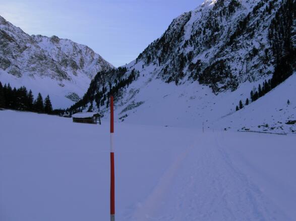 Der Weiterweg ist mit Schneestangen ausgesteckt und führt zur sichtbaren Talverengung.