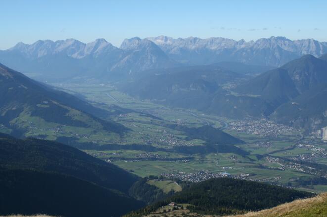 Tiefblick von der Nockspitze auf das Tiroler Oberland. Am unteren Bildrand ist die Birgitzer Alm gut erkennbar.
