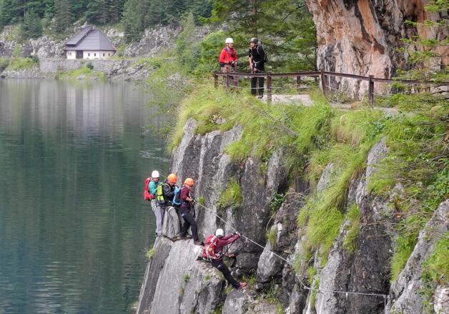 Man quert zwischen Wanderweg und Seeoberfläche.