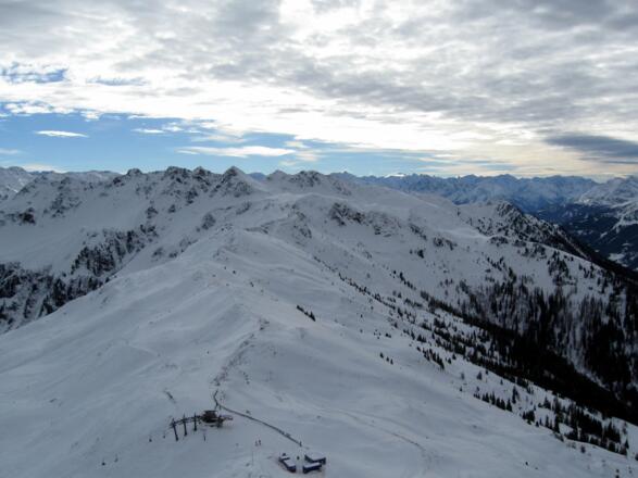 Blick vom Gipfel hinunter auf die Bergstation des Sesselliftes. Am Gratrücken entlang erheben sich Hochstand und Standkopf
