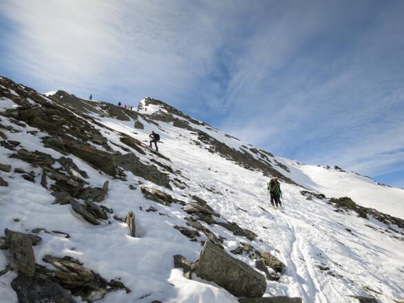 ... zum Skidepot. Oben am Grat absteigende Tourengeher.