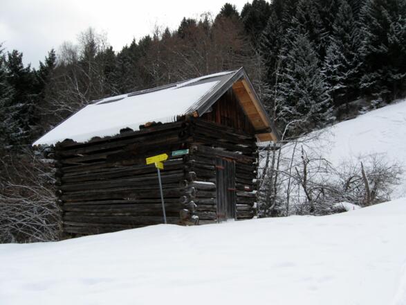 Hinter dieser Hütte geht es vorbei und weiter zum Waldrand.