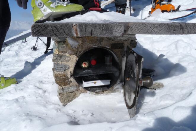 Unterhalb der Sitzbank ist das Gipfelbuch und der Schnaps vor den Unbilden des Wetters geschützt. Einen kleinen Schluck kann man durchaus genießen. Als Dank sollte man ein paar EURO-Münzen zurücklassen, damit für Nachschub gesorgt werden kann.