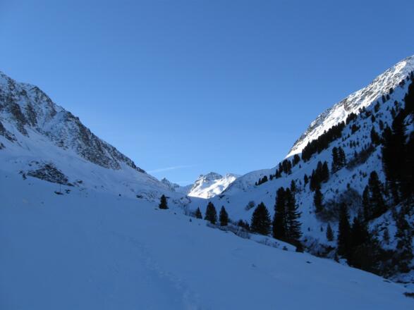 Dann weitet sich das Tal wieder. Hinten taucht das Gipfelziel in der Sonne auf.