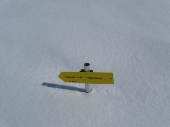 Wegweiser versunken im Schnee.