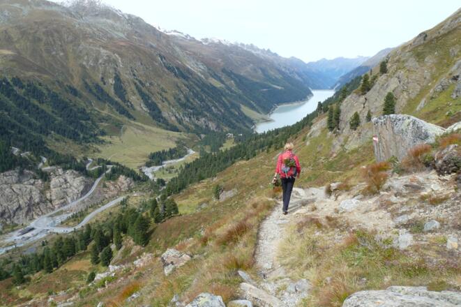 Über schöne alpine Wiesen und hoch über dem Gletscherbach des Gepatschferners geht es mit Blick auf den Gepatschstausee und die Ausflugsstraße ins Tal.