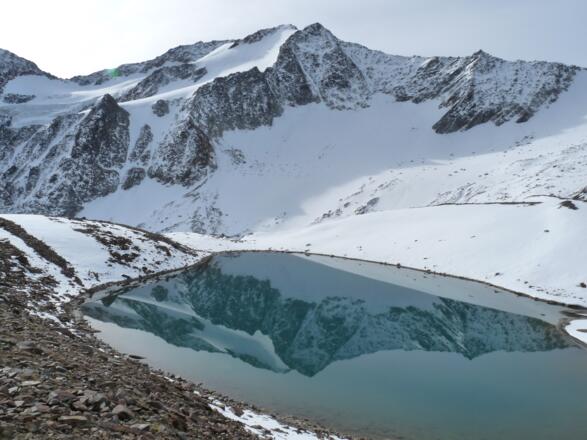 Die Bergwelt spiegelt sich in einem kleinen See auf über 2800 m. Im Frühherbst ist in diesen Höhenlagen bereits mit Schnee zu rechnen.