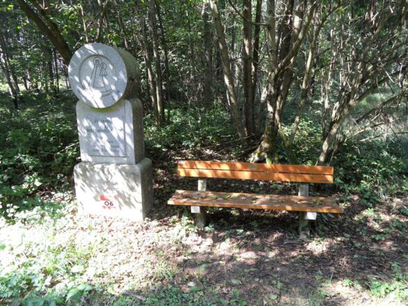 Neben der Parkbank befindet sich ein Gedenkstein 25 Jahre Weitwanderweg.