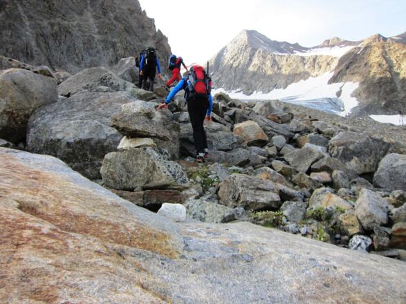 Steinmänner unterstützen die Wegfindung durch das Blockgelände. Hinten sichtbar die beiden Gletscher - unten der Alpeiner Kräulferner, oben der Seespitzferner. Die Felsbarriere dazwischen erfordert kurze Felskletterei.