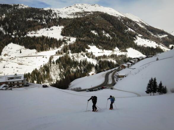 Ein große Wiese führt vom Parkplatz (unten) zum Waldrand. Im Hintergund der Sumpfkopf (2341 m).