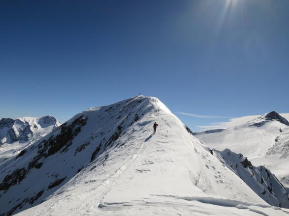 Der Westgrat zum Gipfel ist an wenigen Stellen recht schmal (Absturzgefahr) und nach Süden häufig stark überwechtet. Hinten links Hoher Riffler, rechts der Große Kaserer.