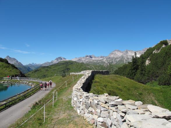 Lecher Mauer am Kriegersattel, die vom Künstler Daniel Nikolaus Kocher gestaltet wurde; auf den Steinen der Mauer sind die Lecher Bürger verewigt.